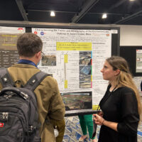 Photo of a student presenting a poster at a science conference